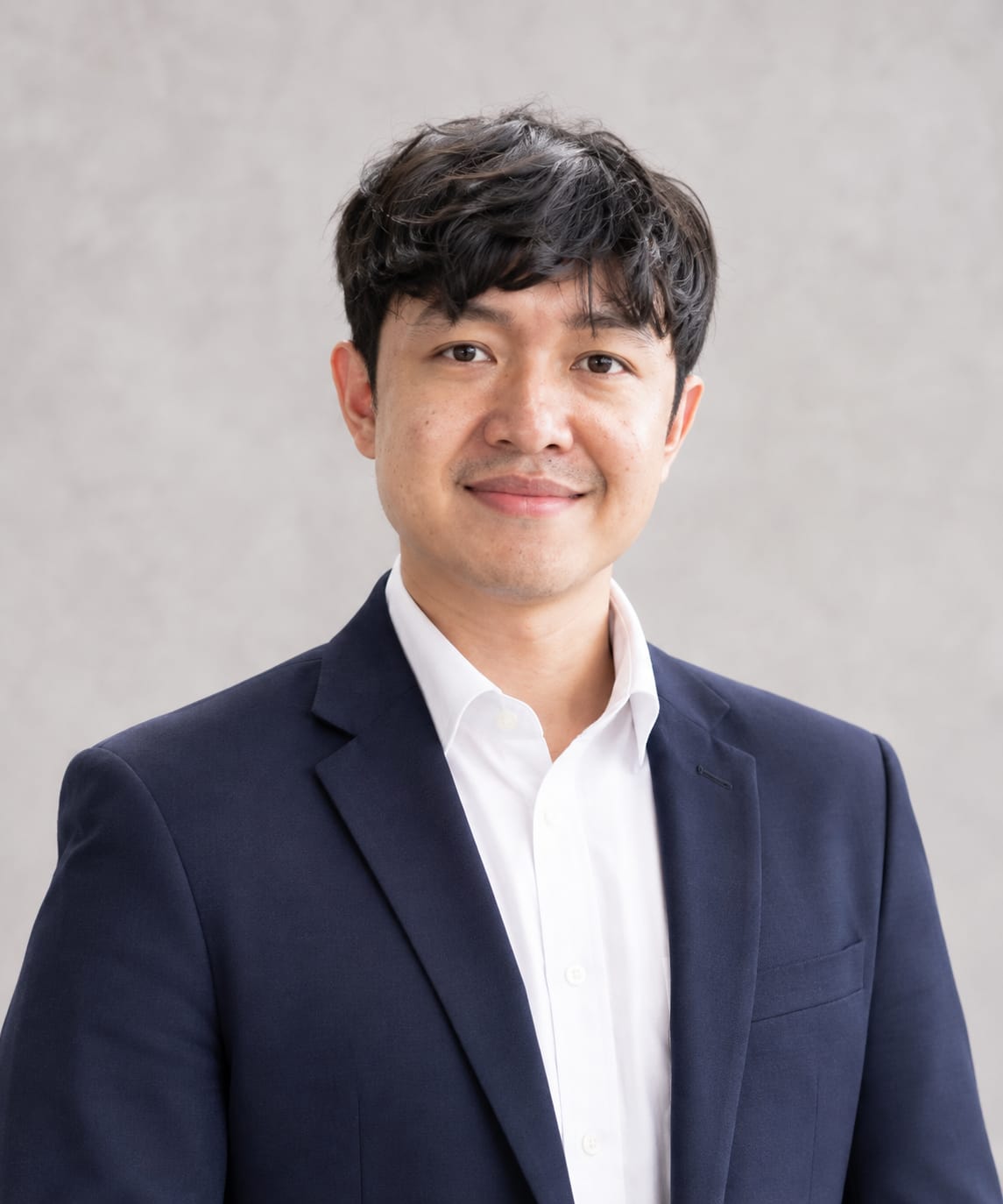 Portrait of Rahmat Fajri smiling, wearing a navy blazer over a white shirt